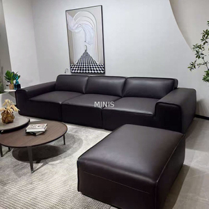 Sof&aacute; de cuero negro c&oacute;modo agradable de la sala de estar con el otomano