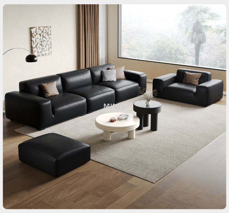 Sof&aacute; de cuero negro c&oacute;modo agradable de la sala de estar con el otomano